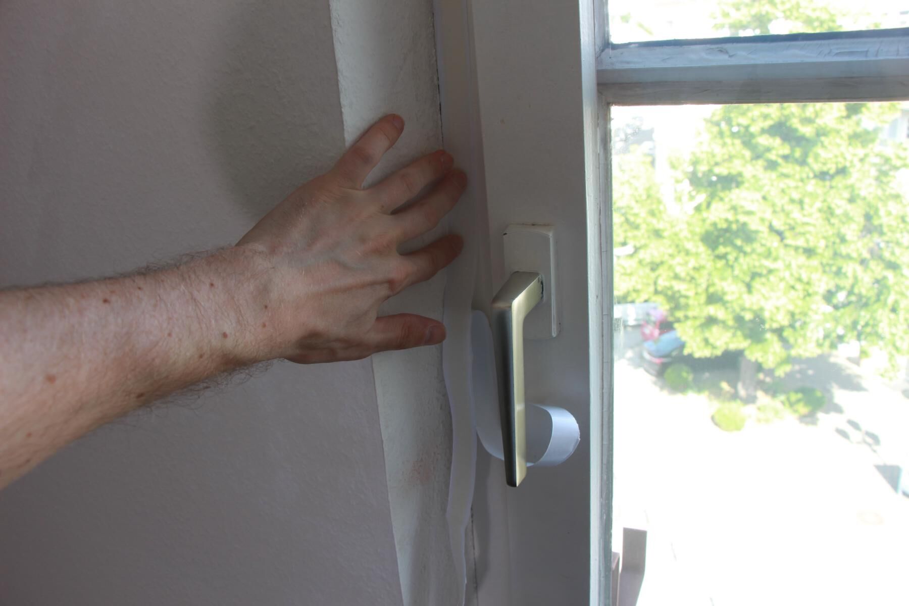 Das Klebeband der Fensterabdichtung wird am Fensterrahmen angebracht.